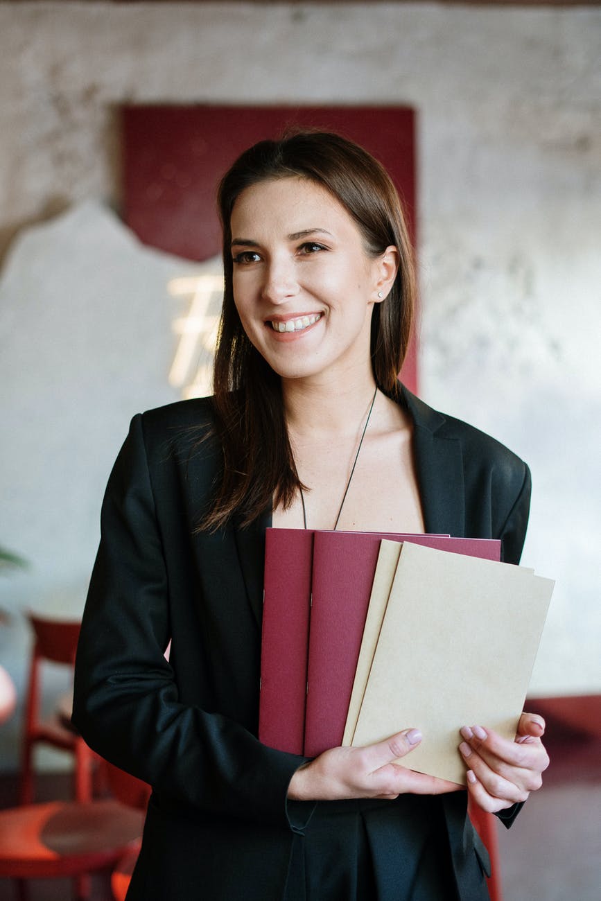 woman in black blazer holding red book